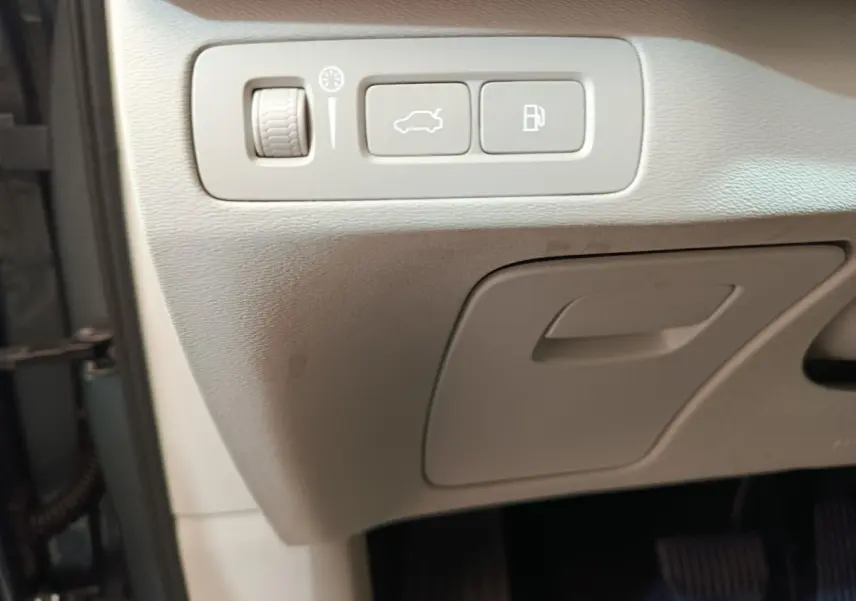 Détail intérieur montrant les commandes d'ouverture du coffre et du réservoir sur la planche côté conducteur du Volvo XC90 gris clair.