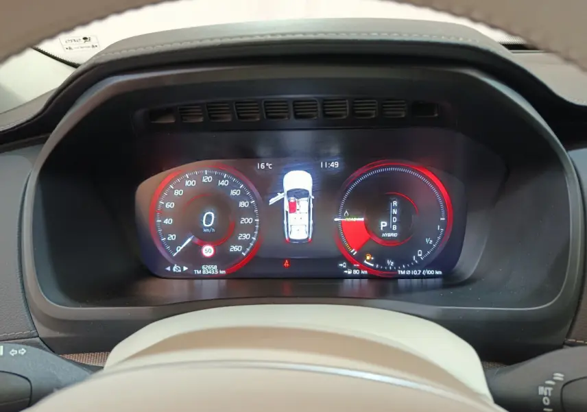 Tableau de bord numérique du Volvo XC90 T8 hybride, affichage vitesse et énergie en rouge et noir, vue frontale rapprochée.