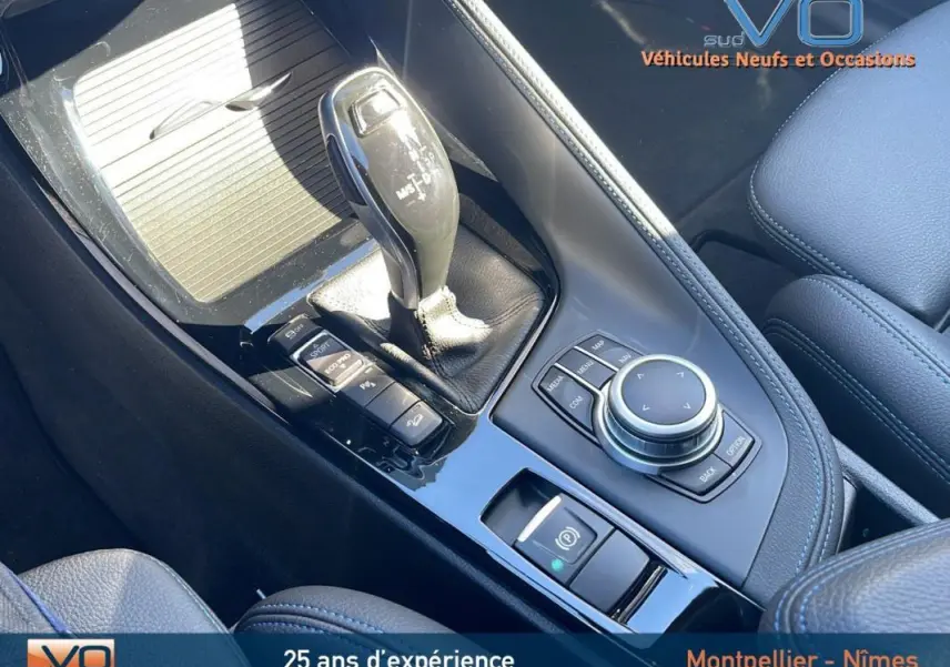 Vue rapprochée de la console centrale noire de la BMW X2 M35i 2019, avec levier de vitesse et commandes multimédia visibles.