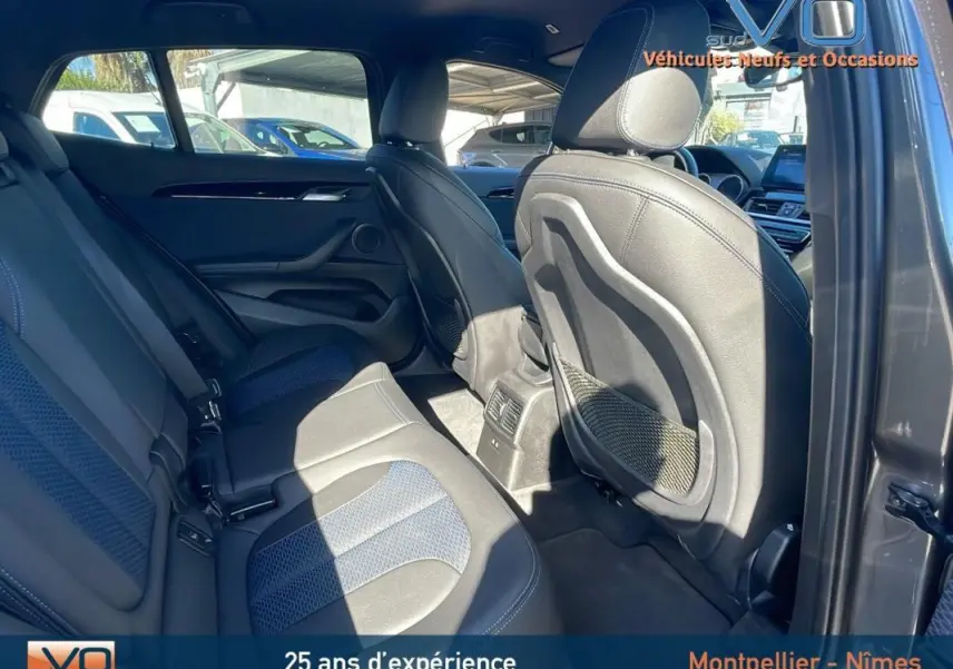 Vue intérieure arrière côté droit du BMW X2 gris, montrant les sièges en cuir et les aérations centrales.