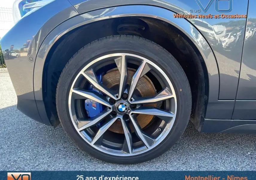Gros plan sur la jante alliage 19 pouces et l’étrier de frein bleu du BMW X2 gris côté avant droit.