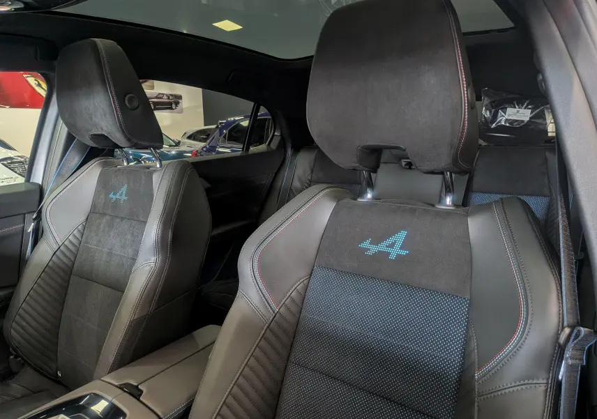 Gros plan sur les sièges avant en cuir et alcantara gris avec logo Alpine bleu, intérieur du Renault Rafale 2025.