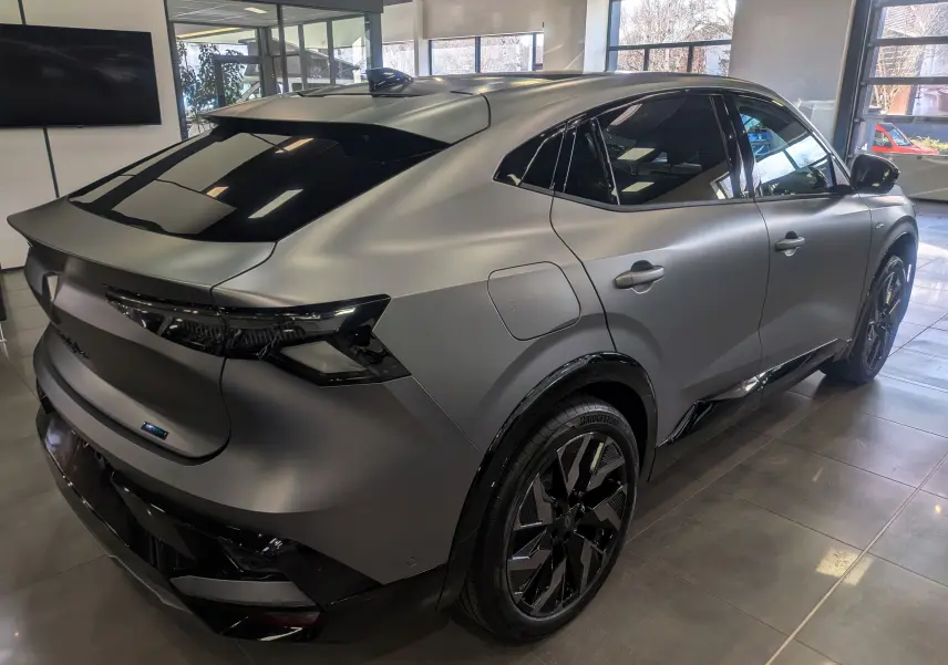 Vue 3/4 arrière droite d’une Renault Rafale E-TECH gris schiste satin avec jantes noires et vitres teintées en showroom.