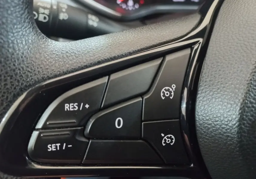 Gros plan sur les commandes de régulateur de vitesse au volant d’une Renault Clio blanche de 2020.