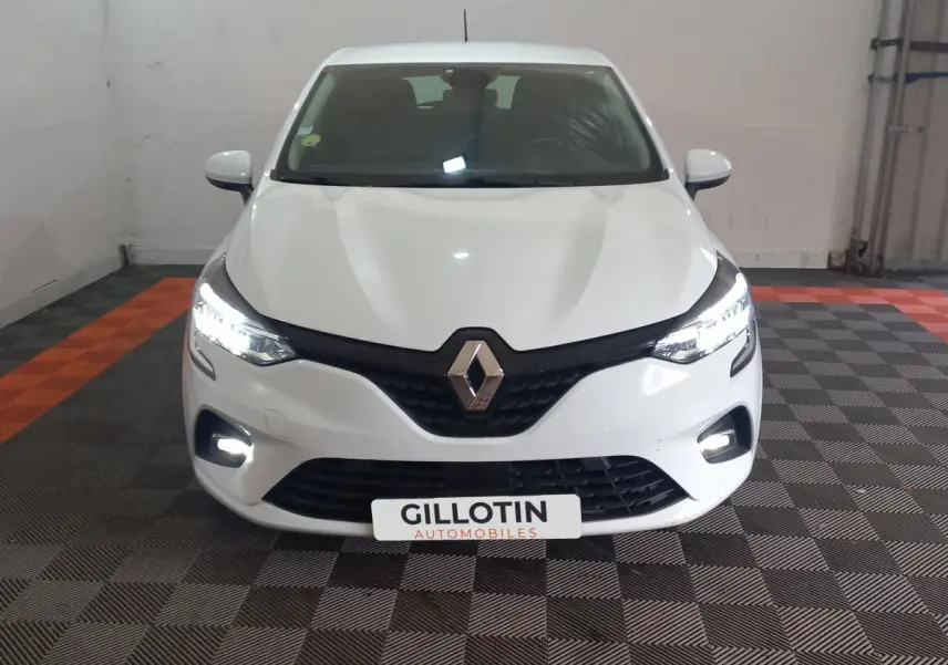 Vue frontale d'une Renault Clio Air Nav Blue dCi 85 blanche avec phares LED allumés dans un garage.