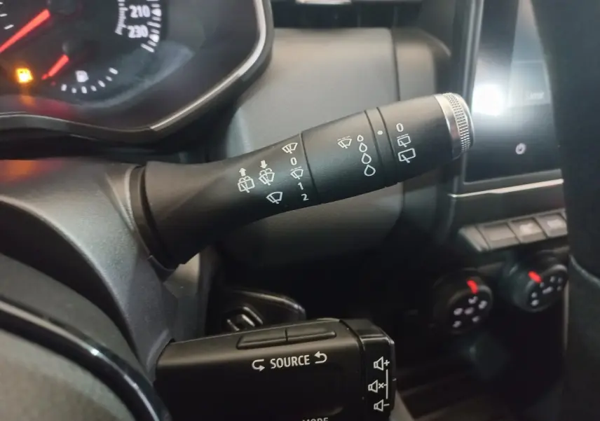 Gros plan intérieur sur la commande d’essuie-glace et les boutons multimédias du tableau de bord d’une Renault Clio blanche 2020.