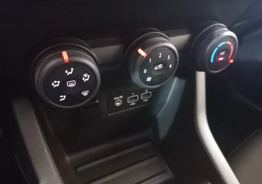 Gros plan sur les commandes de climatisation noire de la Renault Clio blanche, avec réglages de ventilation et température.