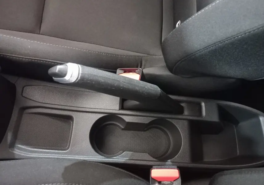 Vue rapprochée de la console centrale noire avec frein à main et porte-gobelets de la Renault Clio Air Nav Blue dCi 85 blanche.