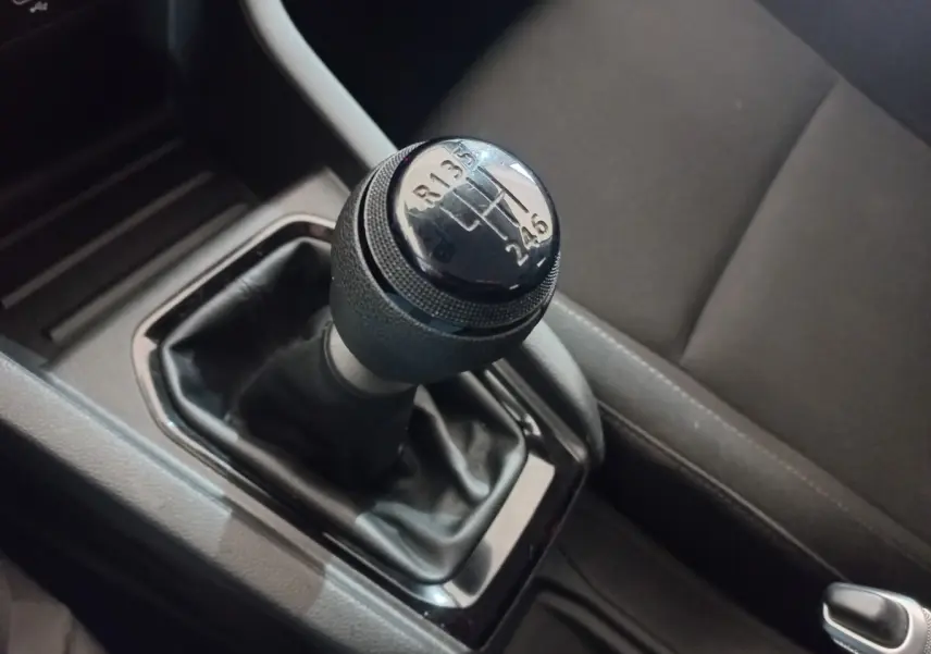 Gros plan sur le levier de vitesses manuel noir de la Renault Clio blanche, avec siège conducteur gris en arrière-plan.