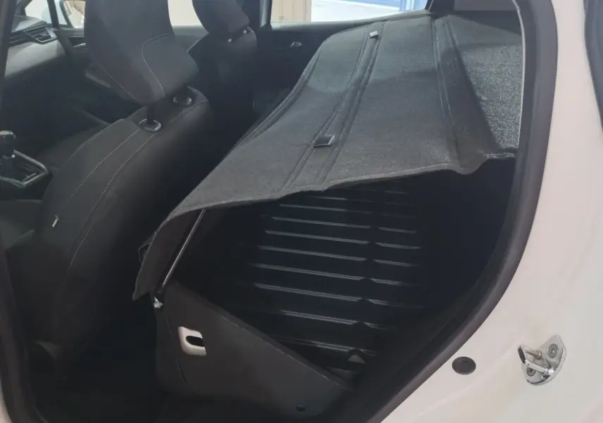 Vue intérieure côté droit de la Renault Clio blanche 2020 avec banquette arrière rabattue et coffre ouvert.