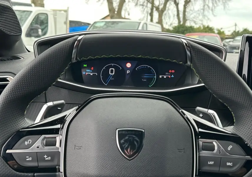 Vue intérieure centrée sur le volant Peugeot 208 Hybrid 110 e-DCS6 GT avec cockpit numérique et coutures vertes.