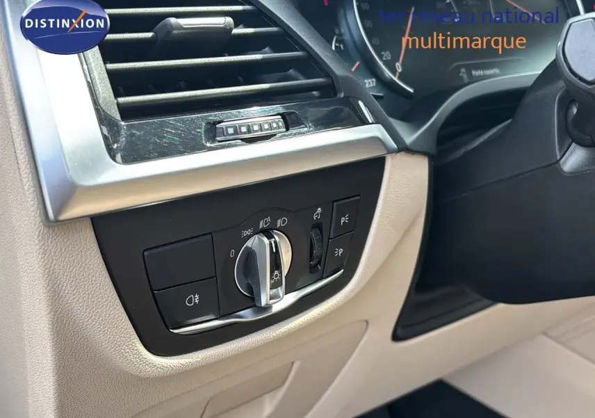 Détail du tableau de bord beige d'une BMW X4 XDRIVE 30D 2019 avec commandes d'éclairage et aérateur.