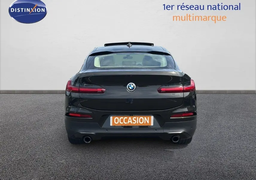 Vue arrière d'un BMW X4 XDRIVE 30D Sparkling Storm Métal avec feux LED et double sortie d'échappement visible.