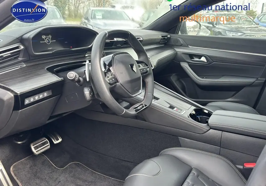 Vue intérieure côté conducteur du Peugeot 508 SW Hybrid 225 GT e-EAT8 avec volant cuir et inserts carbone.