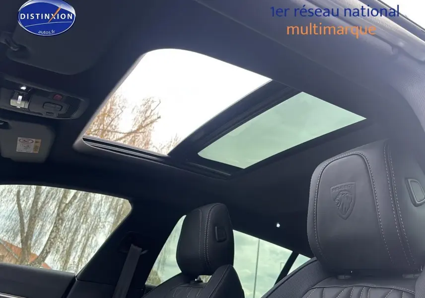 Vue intérieure du toit ouvrant panoramique et des sièges avant en cuir noir du Peugeot 508 SW Hybrid 225 gris titane 2024.