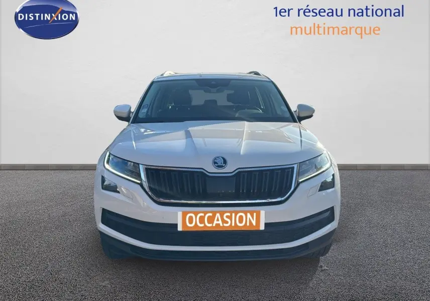 Vue frontale d'un Skoda Kodiaq blanc 2018 avec calandre noire et feux LED allumés sur fond neutre.