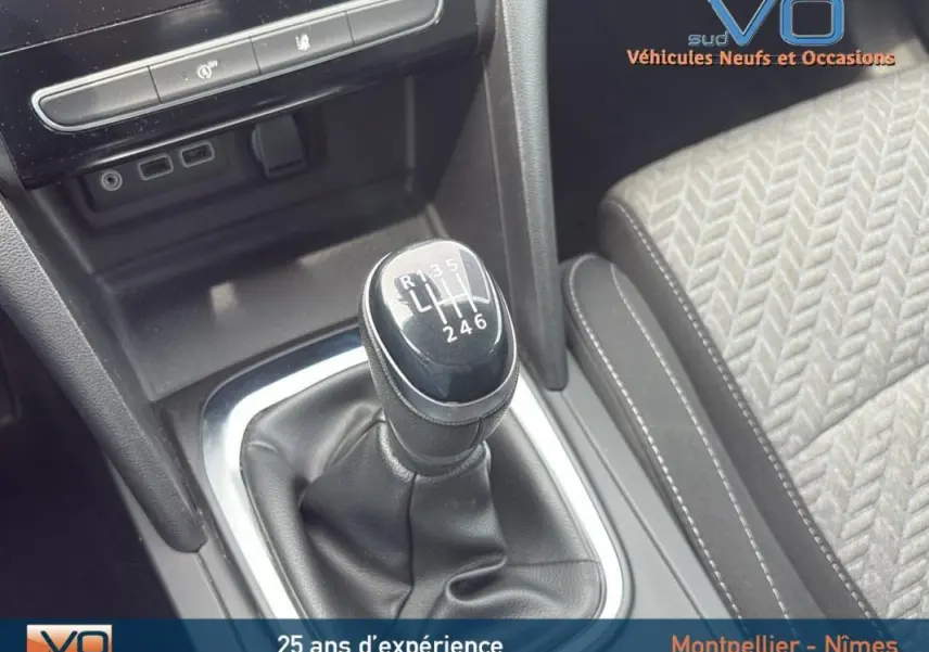 Le levier de vitesses manuel noir de la Renault Mégane IV gris foncé, avec partie centrale et siège tissu à motifs visibles.