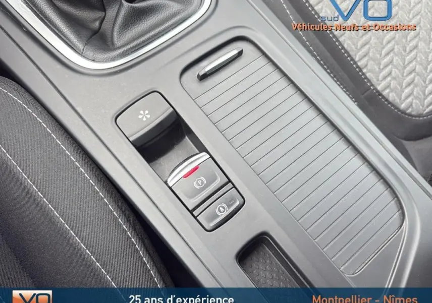 Gros plan sur la console centrale de la Renault Mégane IV Berline gris foncé, mettant en valeur la boîte manuelle et le frein de parking électrique.