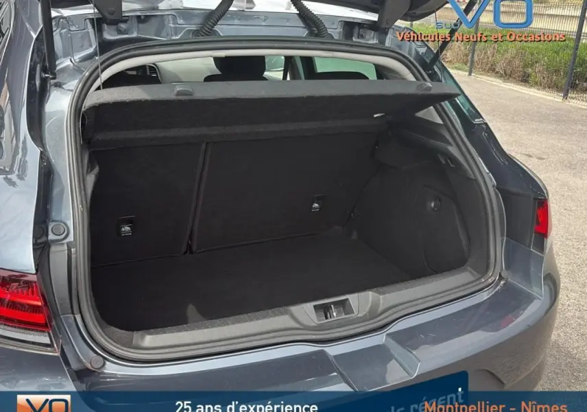 Coffre ouvert vu de l'arrière d'une Renault Mégane IV Berline gris foncé, montrant l'espace de chargement vide.