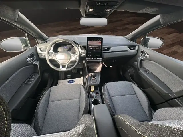 Vue intérieure avant du Renault Captur 2025, tableau de bord moderne avec écran central vertical et sièges gris.
