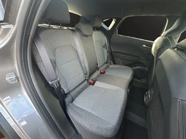 Vue intérieure du siège arrière côté gauche du Renault Captur 2025 gris Cassioppe avec toit noir, montrant les ceintures et finitions tissu.