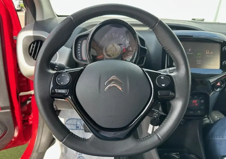 Volant en croûte de cuir de la Citroën C1 rouge Scarlet, vue centrée sur le tableau de bord et l'écran tactile.