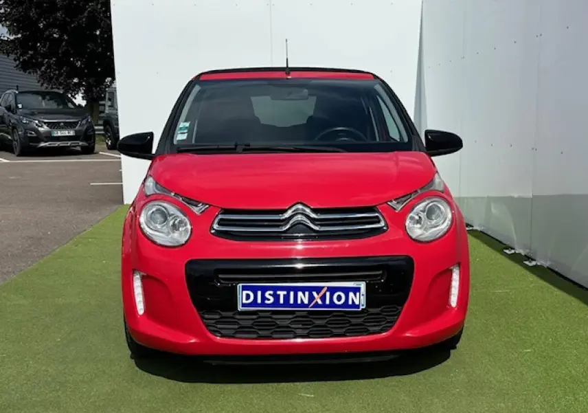Vue frontale d'une Citroën C1 rouge Scarlet avec calandre chromée et feux diurnes à LED verticaux.