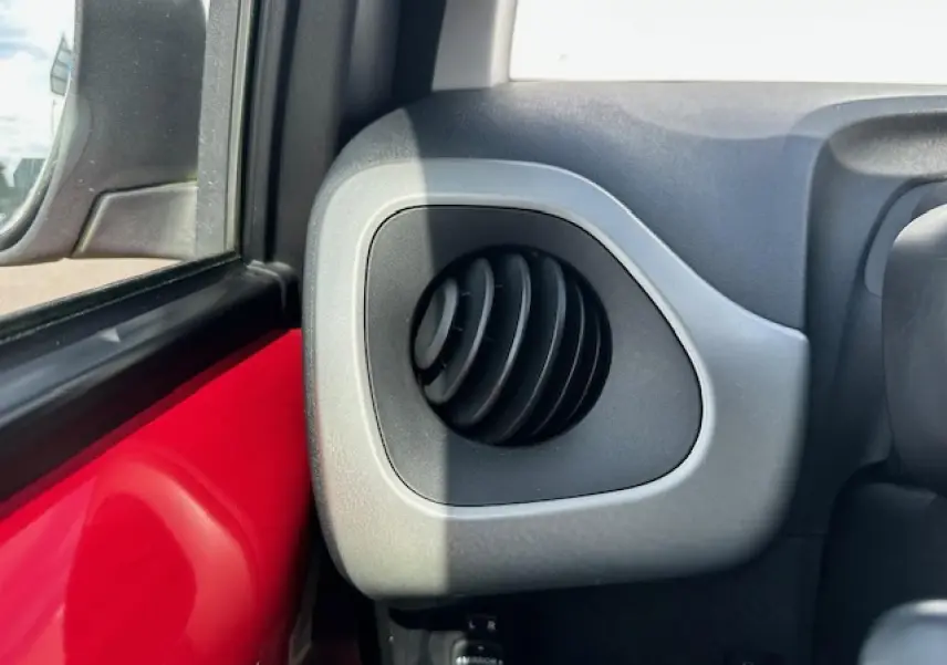 Détail de la sortie d'air ronde côté gauche sur tableau de bord gris d'une Citroën C1 rouge Scarlet 2014
