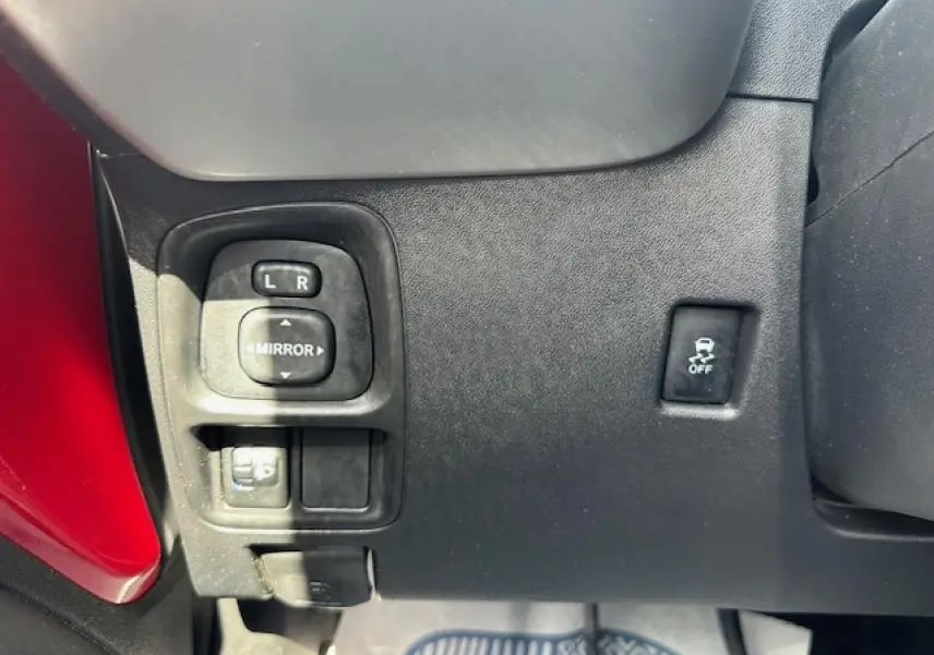 Panneau de commandes côté gauche avec réglage des rétroviseurs et bouton ESP sur une Citroën C1 rouge Scarlet 2014.