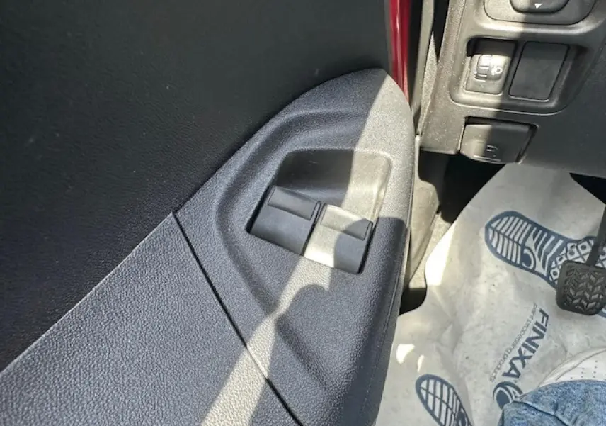 Détail des commandes de lève-vitres côté gauche dans une Citroën C1 rouge Scarlet de 2014.