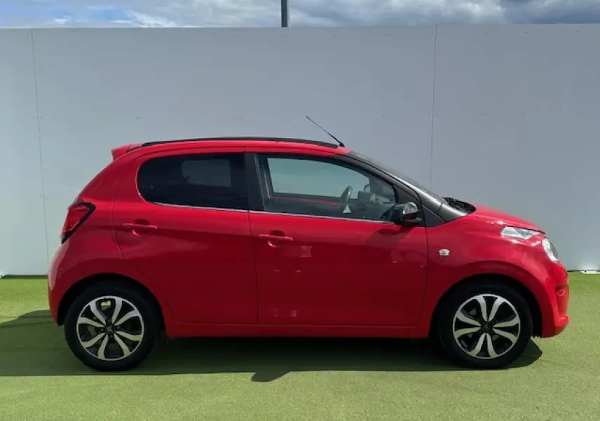 Profil côté gauche d'une Citroën C1 rouge Scarlet avec jantes alliage noires et toit ouvrant souple noir