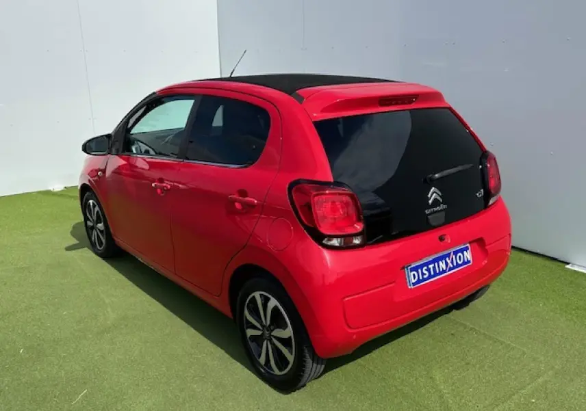 Vue 3/4 arrière droite d'une Citroën C1 rouge Scarlet avec toit noir et jantes alliage 15 pouces.