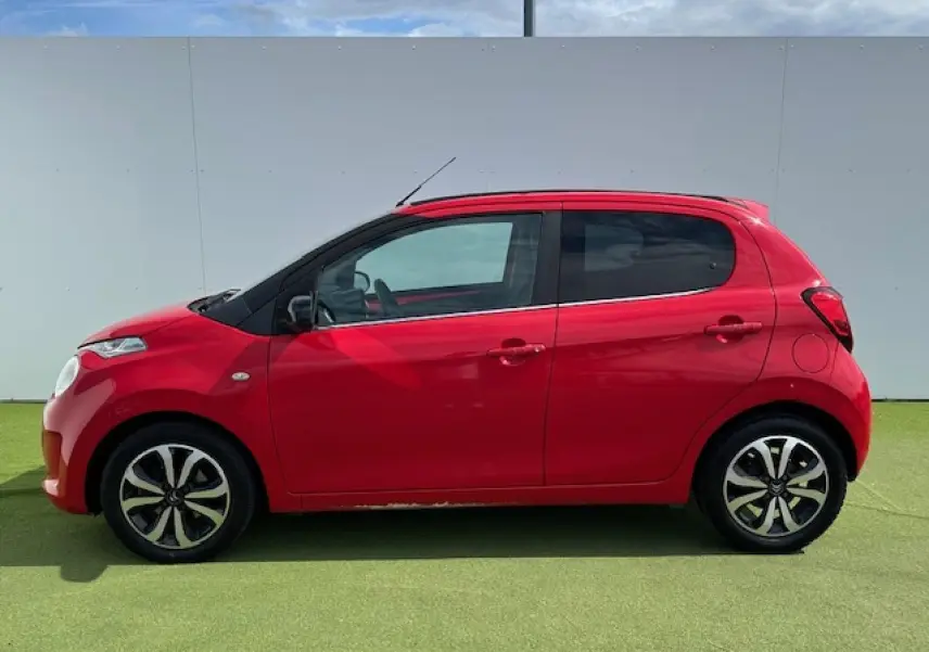 Profil droit d'une Citroën C1 rouge Scarlet de 2014 avec jantes alliage 15 pouces et coques de rétroviseurs noires.