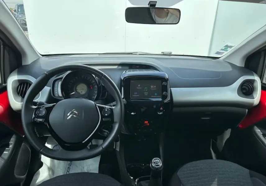 Intérieur avant de la Citroën C1 rouge Scarlet 2014, tableau de bord avec volant cuir et écran tactile central.