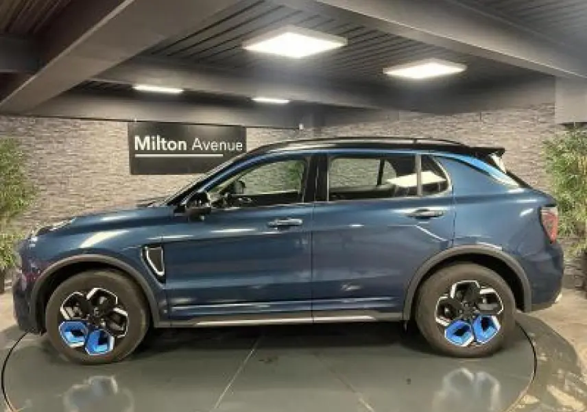 Profil côté gauche du SUV Lynk & Co 01 bleu métallisé avec jantes originales bicolores en showroom.