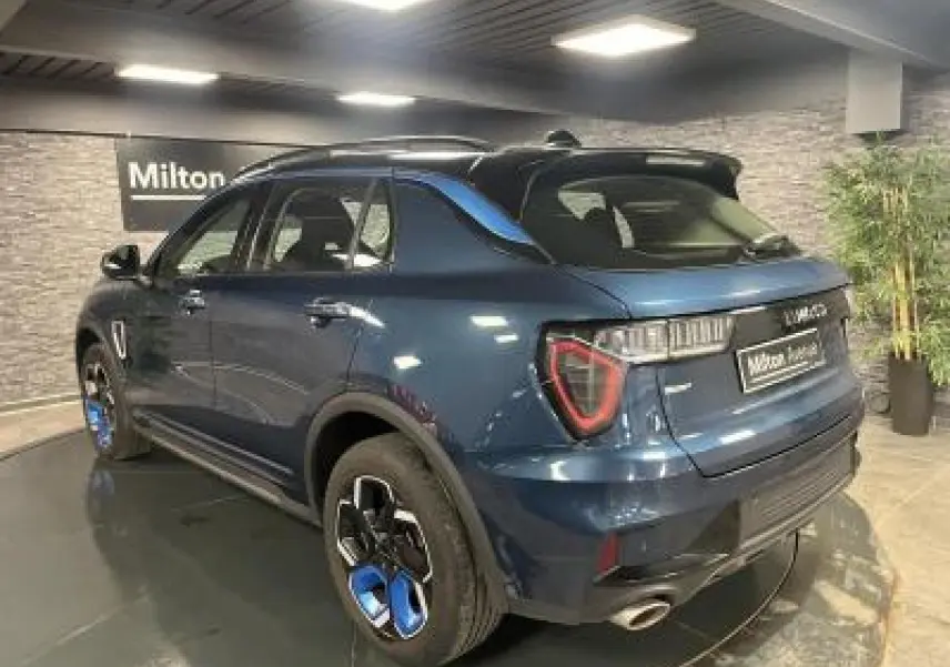 Lynk & Co 01 bleu métallisé vu en 3/4 arrière droit avec jantes bicolores et feux LED distinctifs.