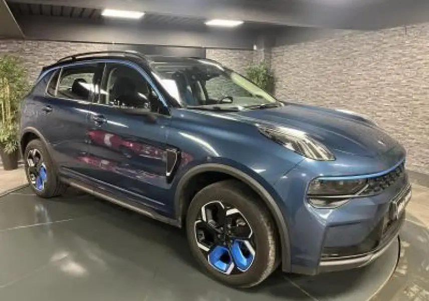 Vue 3/4 avant droite du SUV Lynk & Co 01 bleu métallisé avec jantes alliage noires et bleues dans un showroom.