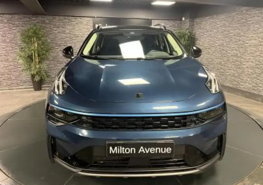 Vue frontale du SUV LYNK & CO 01 bleu métallisé avec calandre noire et plaque "Milton Avenue" visible.