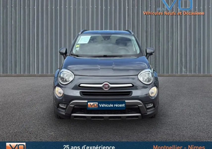 Vue frontale d'un FIAT 500X Cross gris anthracite avec phares ronds et calandre chromée sur parking extérieur.