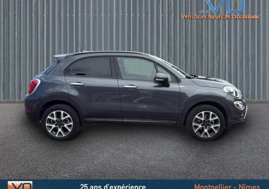 Profil côté gauche d'un FIAT 500X gris anthracite de 2015 avec jantes alliage 17 pouces sur fond urbain.