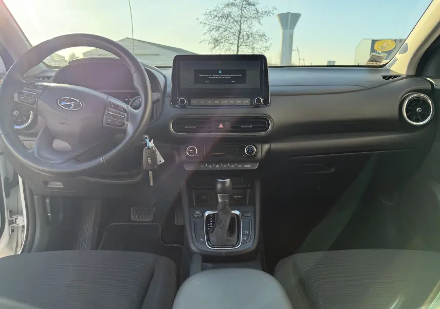 Vue intérieure avant du Hyundai Kona blanc Atlas 2021, tableau de bord moderne avec écran tactile et boîte automatique.