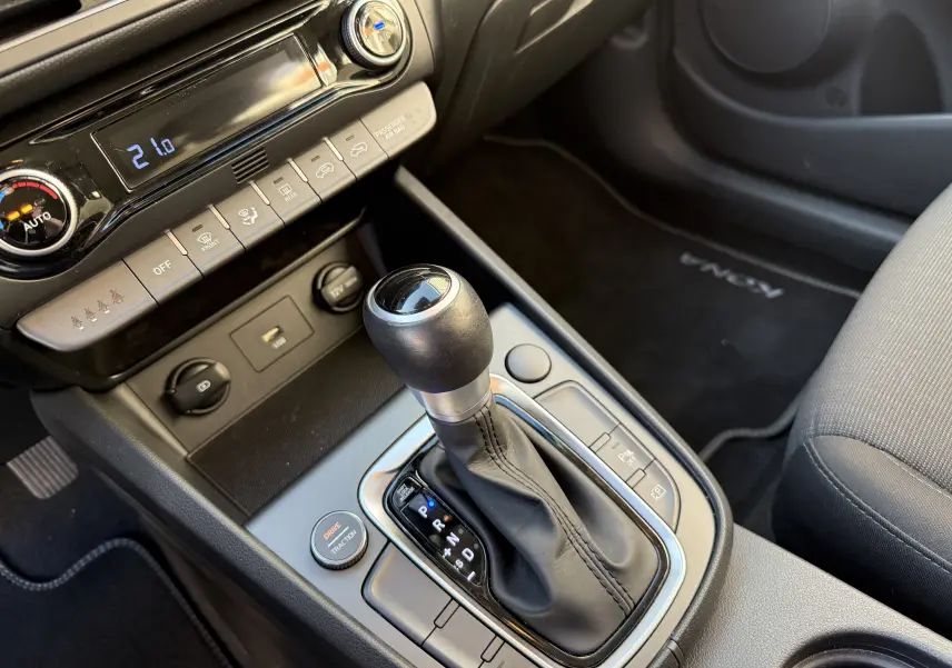 Gros plan sur la console centrale du Hyundai Kona blanc Atlas 2021, mettant en valeur le levier de vitesse automatique et les commandes climatiques.