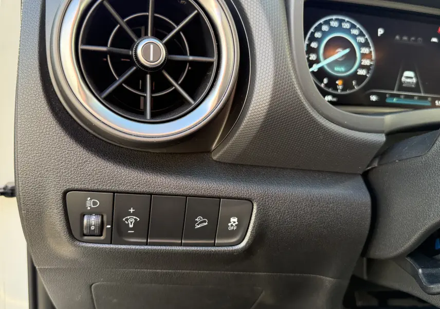 Détail du tableau de bord côté gauche du Hyundai Kona blanc atlas 2021, avec commandes d'éclairage et ventilation ronde.
