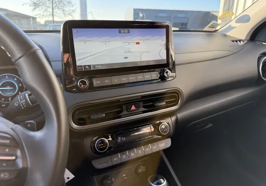 Vue intérieure du tableau de bord du Hyundai Kona blanc Atlas 2021, avec écran tactile de navigation et commandes climatisation visibles.