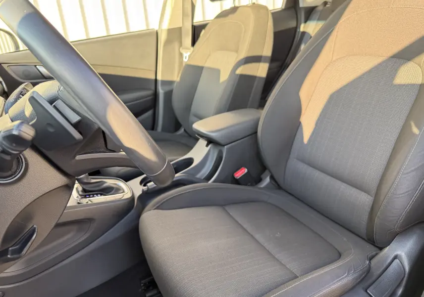 Intérieur du Hyundai Kona 2021, vue côté conducteur, sièges tissu gris noir et console centrale avec boîte auto.