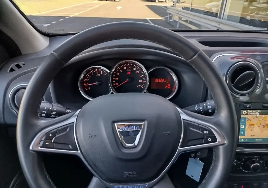 Vue intérieure centrée sur le volant Dacia Sandero Stepway 2020 avec tableau de bord et écran GPS visible.
