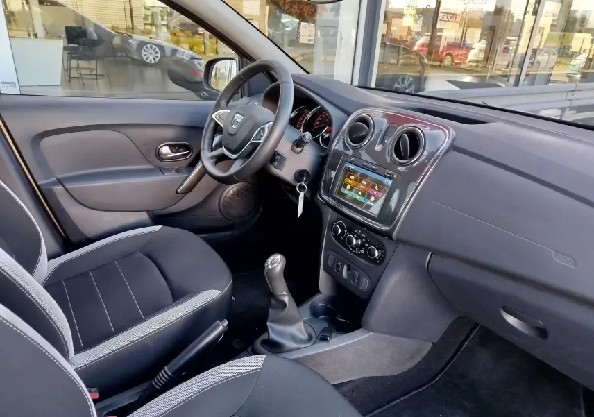 Intérieur côté conducteur de la Dacia Sandero Stepway 2020, tableau de bord gris avec écran tactile et sièges tissu gris.