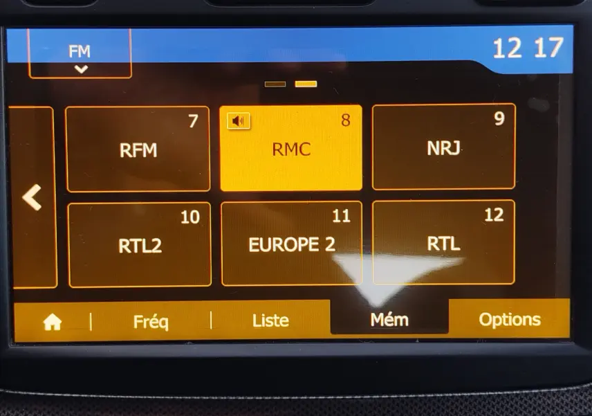 Écran tactile de la radio FM de la Dacia Sandero Stepway 2020 affichant les stations mémorisées en mode orange.