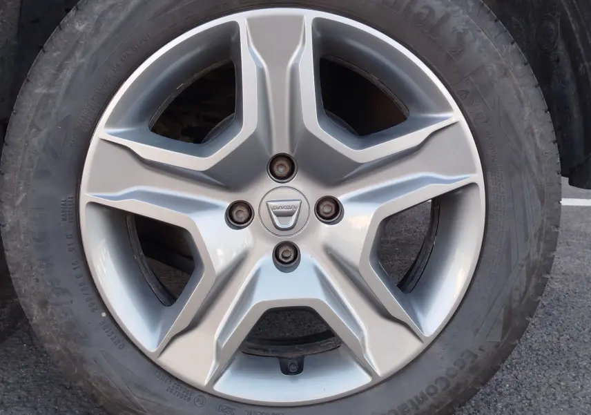 Vue de profil côté gauche d'une Dacia Sandero Stepway beige dune garée sur un sol bitumé.