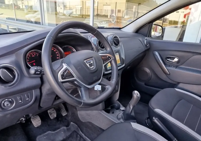 Vue intérieure avant droite du tableau de bord et volant noir de la Dacia Sandero Stepway 2020 en tissu gris.